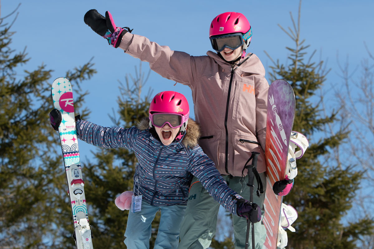 Two excited kids with skis and snowboards